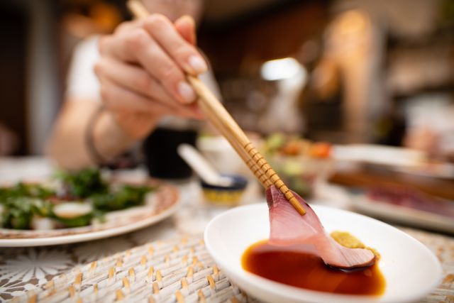 closeup of woman holding sashimi with chopsticks
