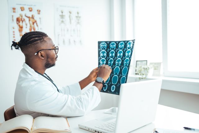 A doctor examines brain scans before suggesting epilepsy treatment options and lifestyle modifications to his patient.