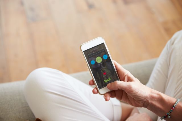 Closeup of a woman's hands holding her phone, looking at her health data