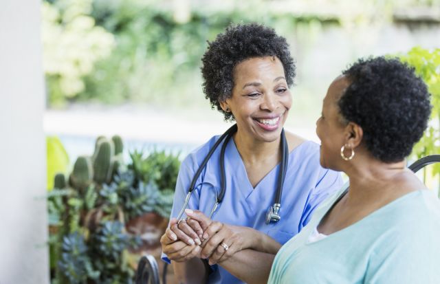 nurse smiling and clutching hand of patient