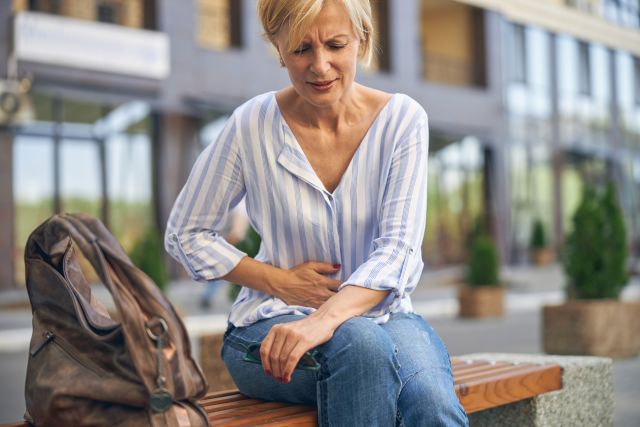 Front view of a frustrated woman suffering from an acute pelvic pain on the bench