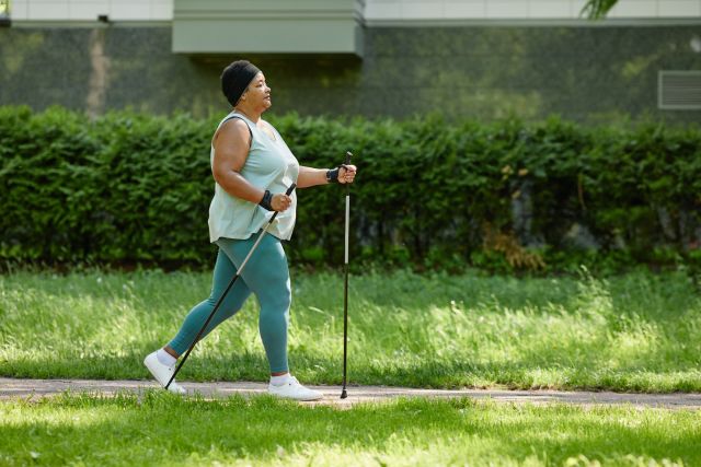woman in exercise clothing nordic walking on a sidewalk to burn more fat