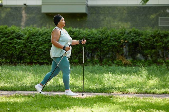 woman in exercise clothing nordic walking on a sidewalk to burn more fat