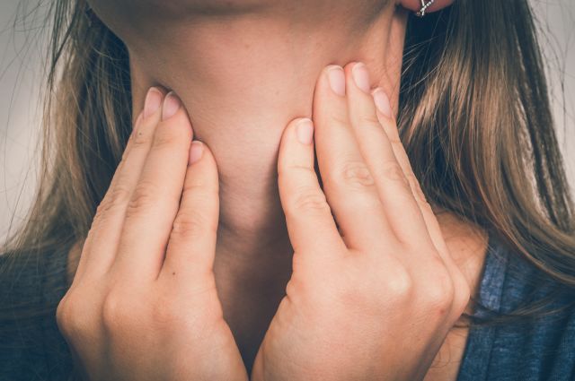 closeup of the throat of a young woman while she puts pressure on it with her hands