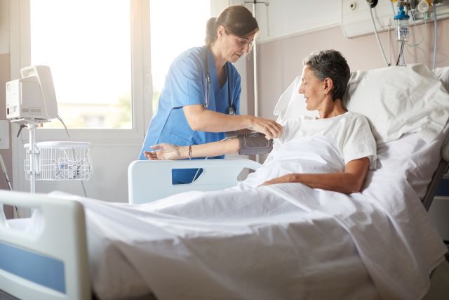 a white woman patient lies in a hospital bed, attended by a white woman nurse, as treatment for sepsis