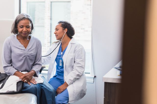 an older Black woman receives a checkup from a healthcare provider
