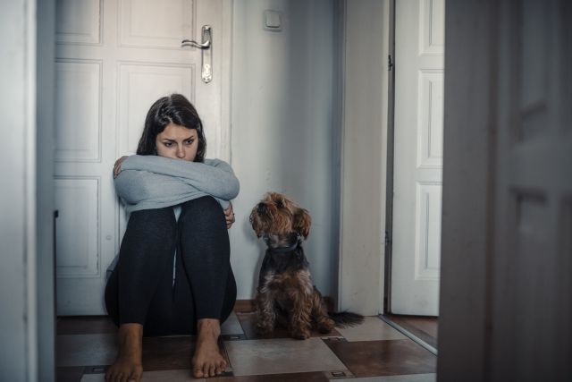 A young woman struggling with low self-esteem and stigma is comforted by her dog. Many people who live with skin conditions avoid social situations and relationships as a result of the condition.