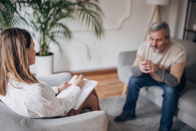 A man living with cancer speaks to a counselor. Working with a counselor is one strategy that can help a person take care of mental health while living with cancer.