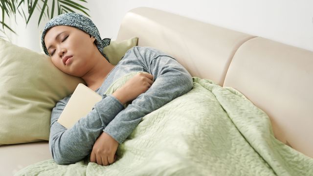 Young woman coping with fatigue from metastatic breast cancer by sleeping on the couch.