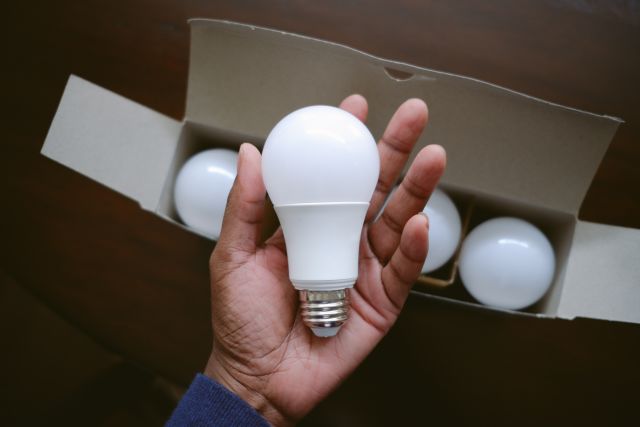 A hand removing a new light bulb from a box. Adding more ambient lighting around the home can be helpful to people living with vision loss.