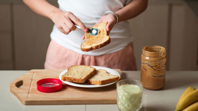Woman in a home kitchen preparing bana roll-ups with almond butter and toast