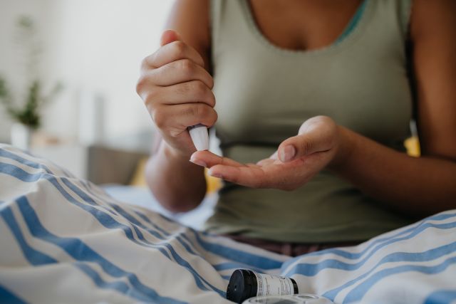 someone checks their blood glucose level using a fingerstick device