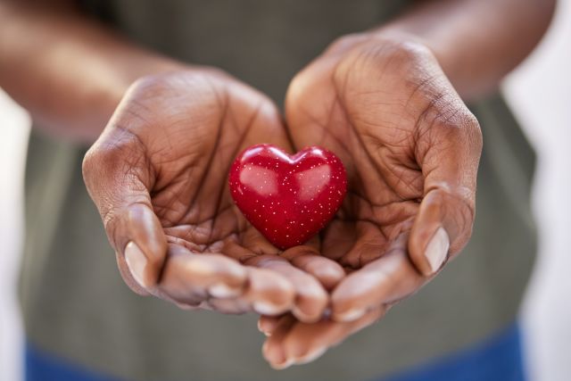 someone holding a red heart in their hand