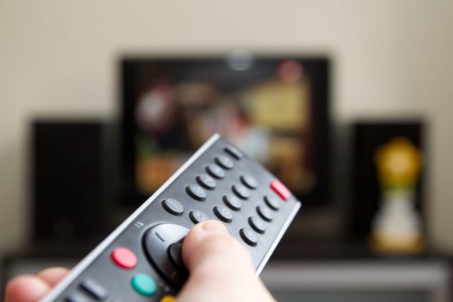 Someone pointing a remote control at a TV screen