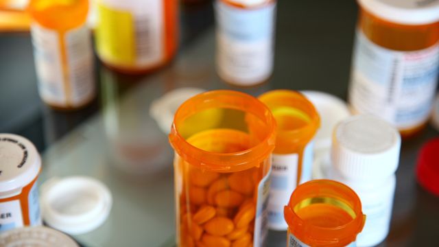 A collection of medication bottles arranged on a pharmacy counter. Treatment for Parkinson's disease often involves a combination of medications to ease symptoms and side effects.