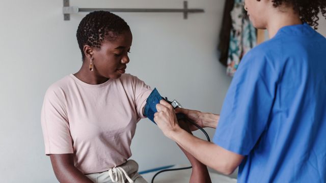 Nurse placing a blood pressure cuff on the arm of a woman during an exam