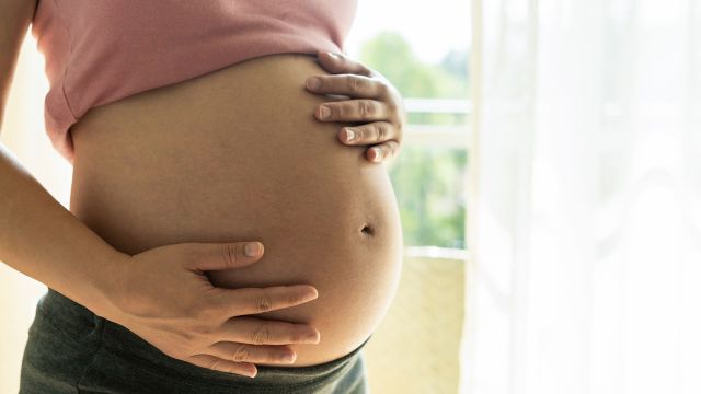 Heavily pregnant woman holding her bare belly