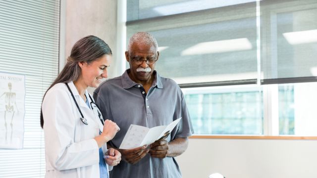 A senior man and his healthcare provider read through a brochure about a thyroid medication at the healthcare provider's office.