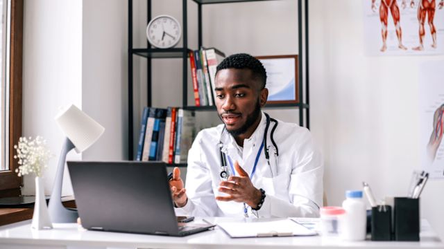 A doctor uses a laptop computer in his office to talk to a patient during a consultation for weight loss treatment.