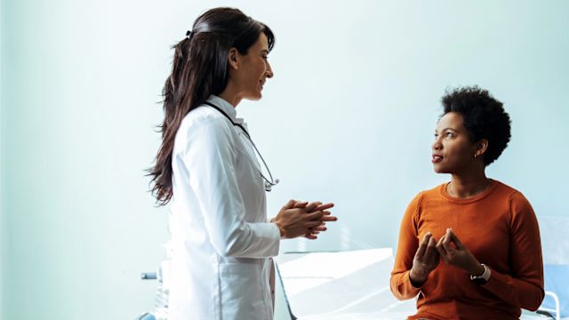 A woman speaks with her neurologist during an appointment to discuss chronic migraine treatment.