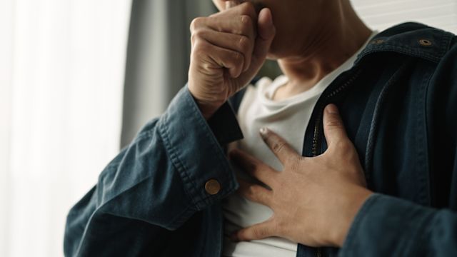 Adult coughing while holding chest