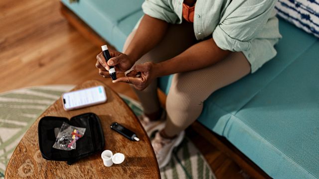 A woman checks her blood glucose levels using a blood glucose meter in her home. Blood glucose control is one of the top goals of managing type 2 diabetes.