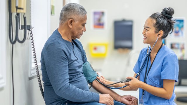 A healthcare provider takes the blood pressure of a male patient. Hypertension, or high blood pressure, can cause damage to the blood vessels and nerves in the eyes.