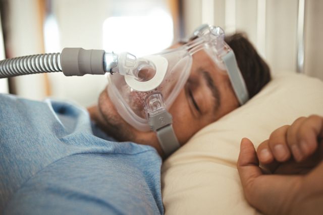 man wearing CPAP mask sleeping in bed