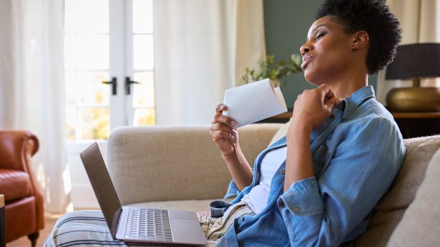 A woman fans herself with a folded piece of paper to cool down during a hot flash.