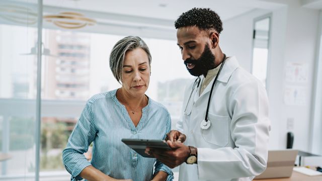 An oncologist explains treatment options and recommendations for MDS to a senior woman using a tablet computer.