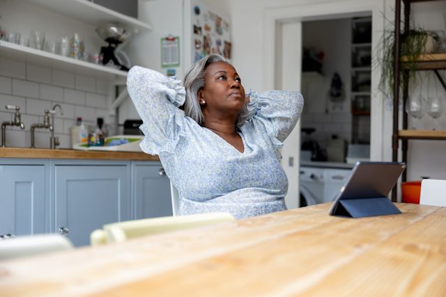 Mature woman working at home on her tablet computer and looking worried and stressed
            