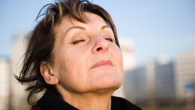 Middle-aged woman takes a deep breath outside.