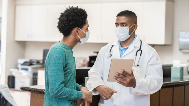 A young man and his healthcare provider discuss treatment for primary immunodeficiency in a healthcare center exam room.