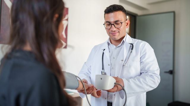 A doctor checks the blood pressure of a female patient. Hypertension is a common complication of kidney disease. 