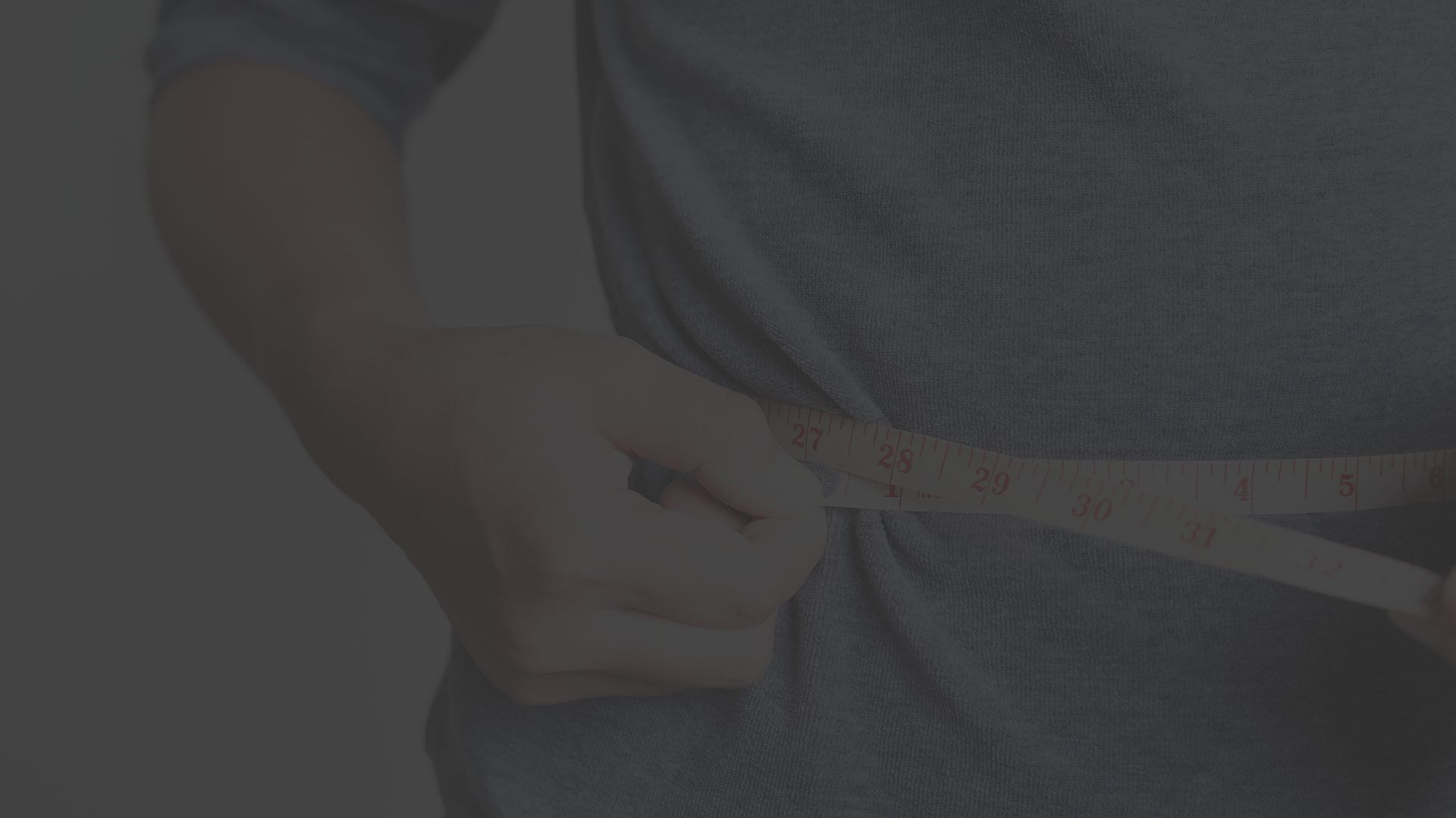 Man measures his waist side with a measuring tape.