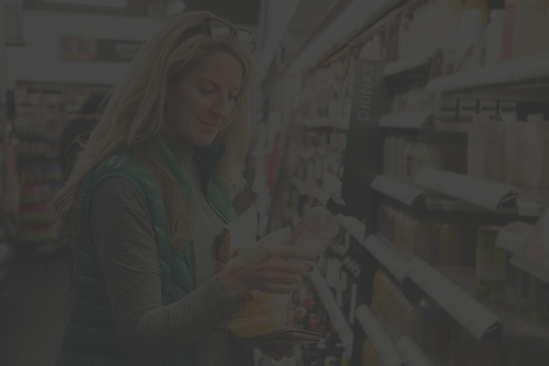 blond woman looking at water bottle in market