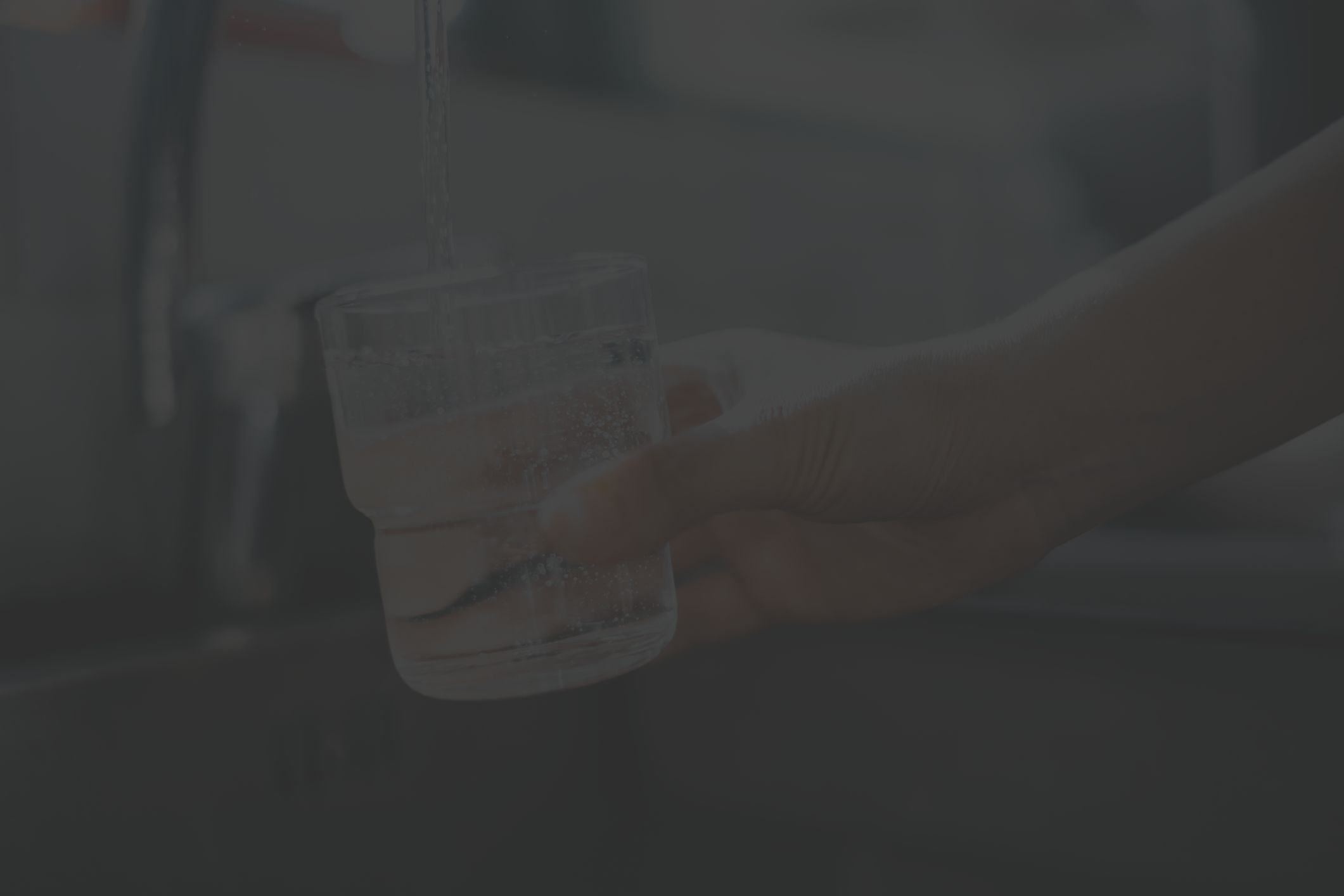 man's hand filling glass of water from faucet