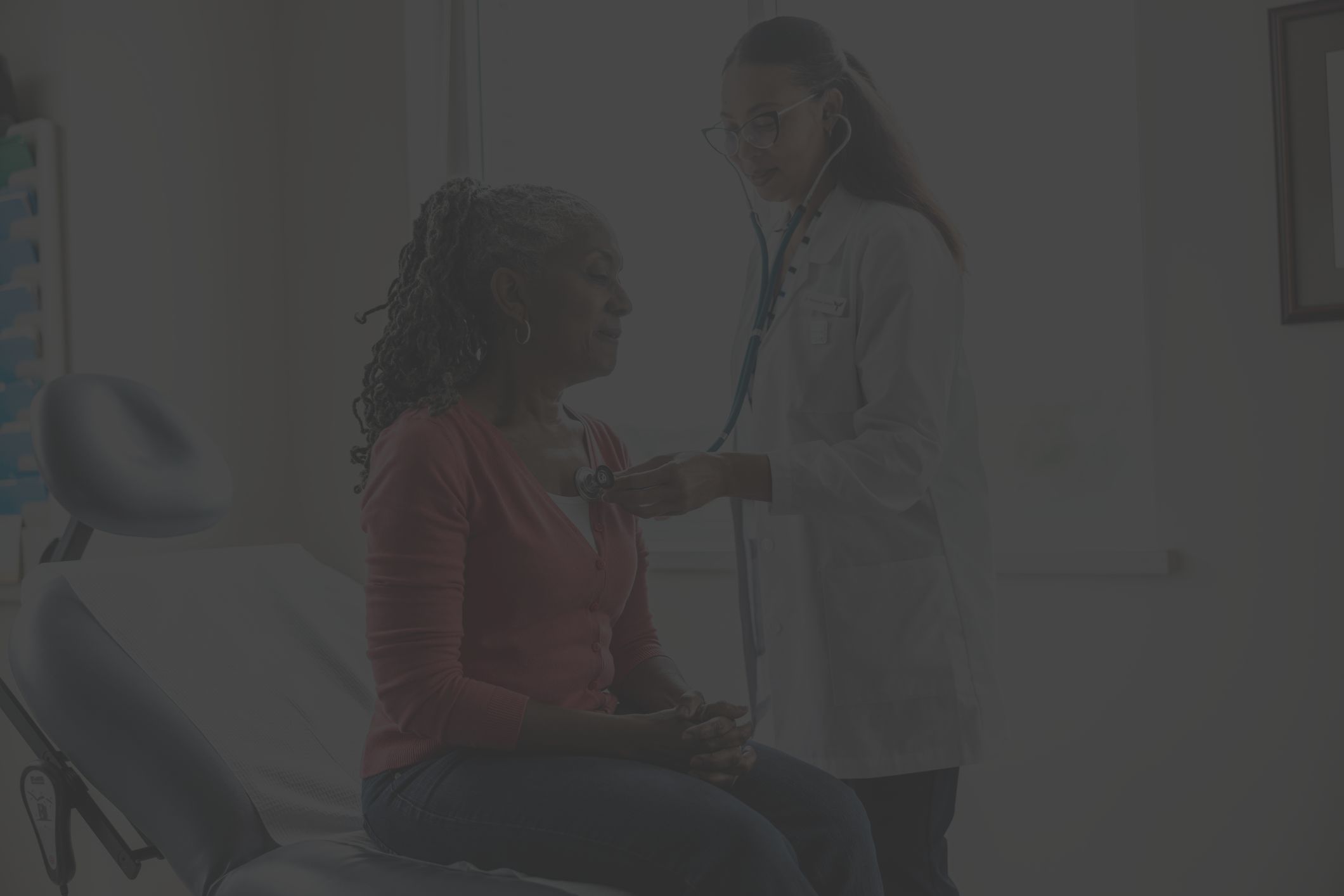 doctor listens to female patient's heart with stethoscope